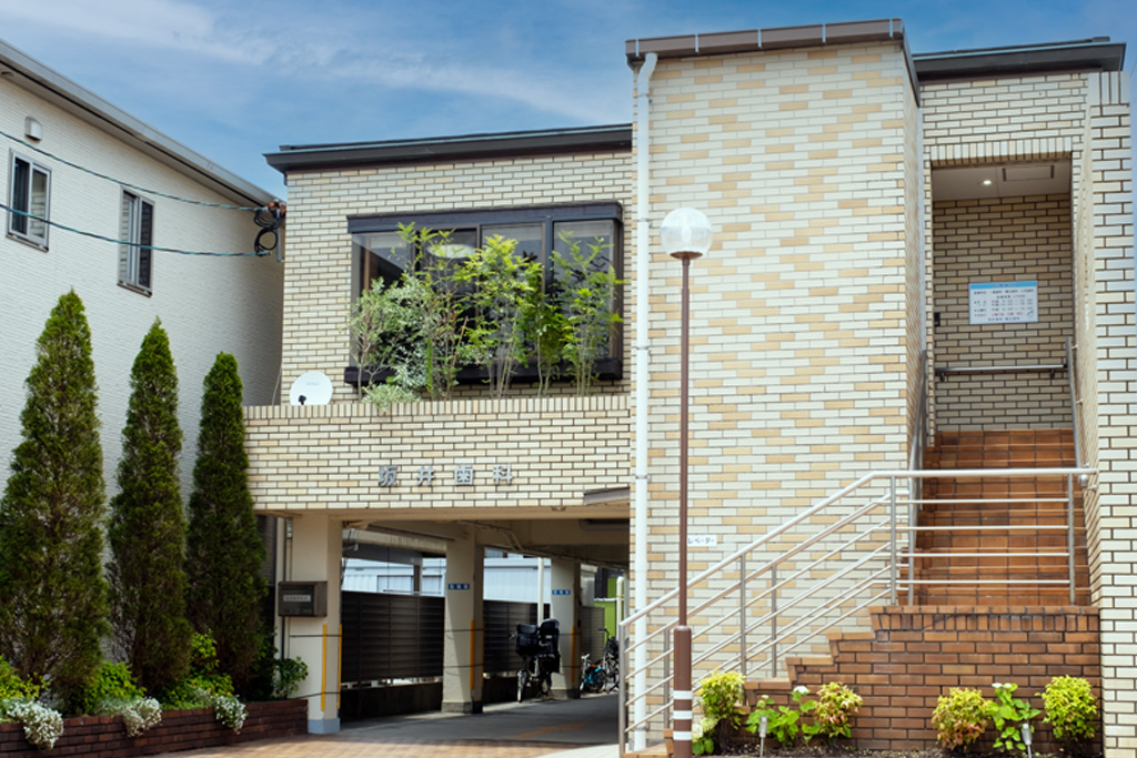 <strong>外観</strong><p>当院は戸建ての歯科医院。レンガ造りの建物です。バリアフリー設計のため、車椅子、ベビーカーの方もエレベーターで無理なく院内へお進みいただけます。また、15台分の駐車場を完備しており、自家用車でお越しの方も安心です。</p> 小城市牛津町・坂井歯科・矯正歯科